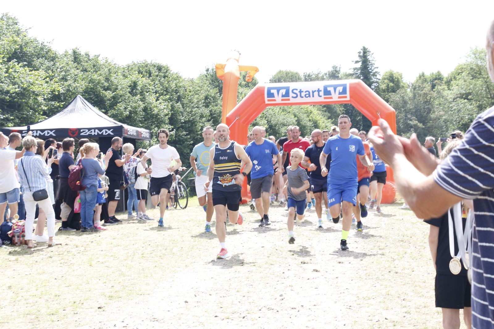 Läuferinnen und Läufer laufen lachend auf das Ziel zu – sonnige Atmosphäre beim Run for Kids