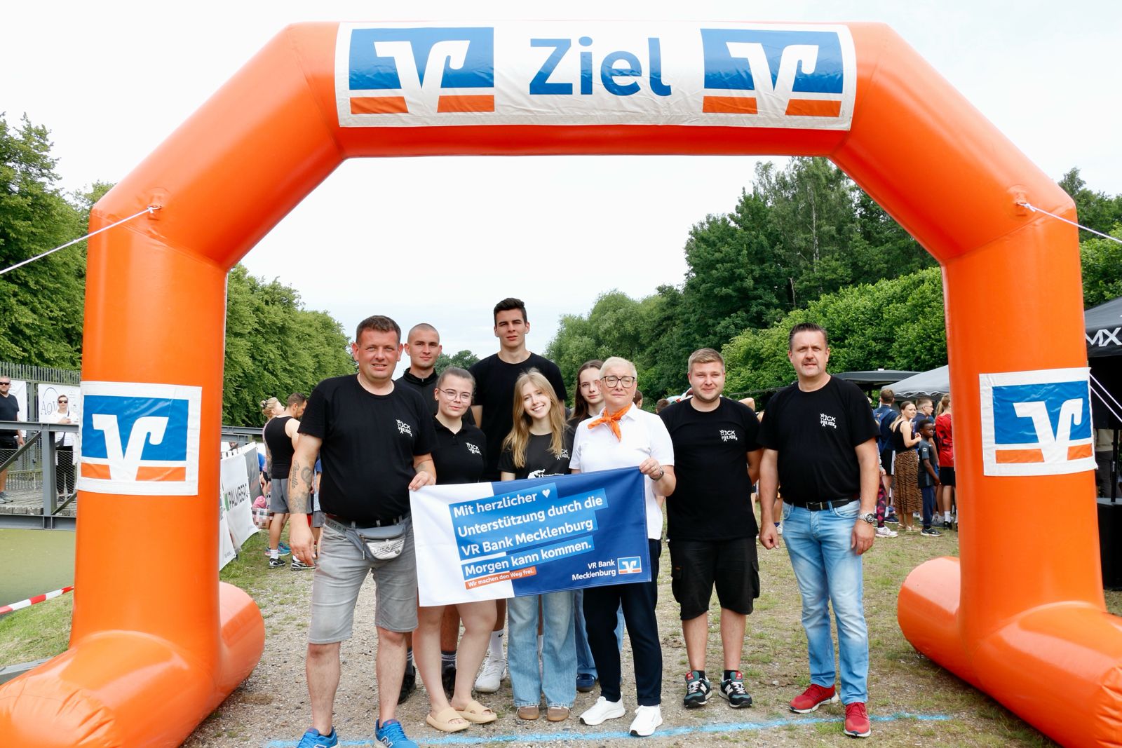 Team Kick for Kids mit VR Bank Mecklenburg-Banner unter dem Zielbogen – Hauptsponsor des Run for Kids